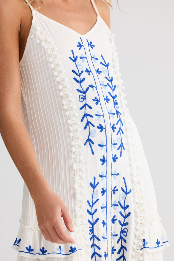 White dress with blue floral embroidery on a white background