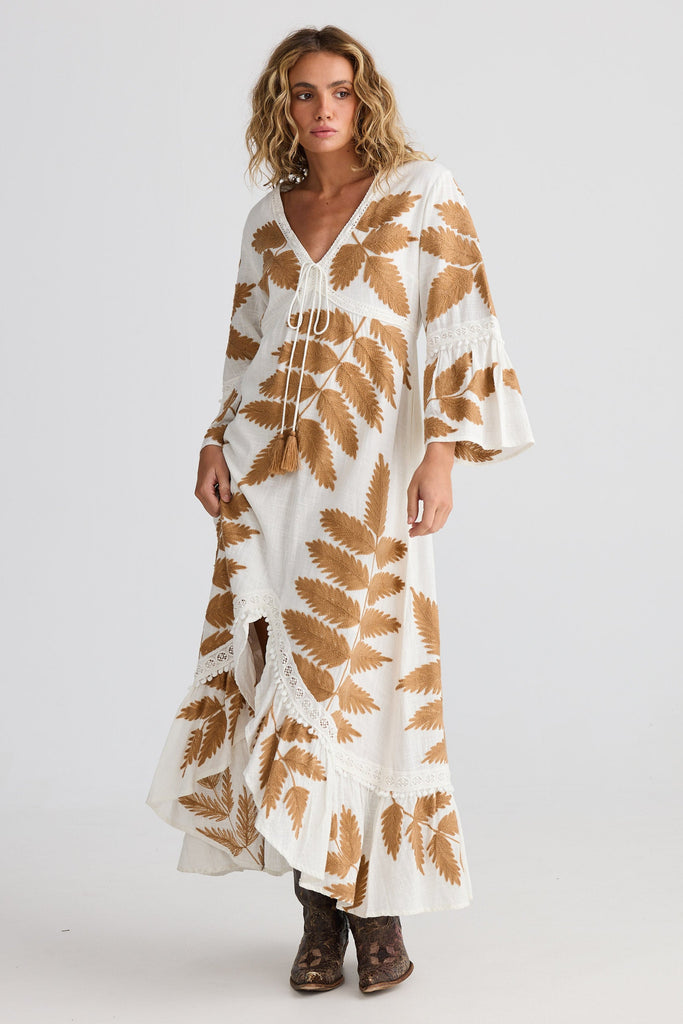 Woman wearing a white dress with brown leaf patterns on a white background