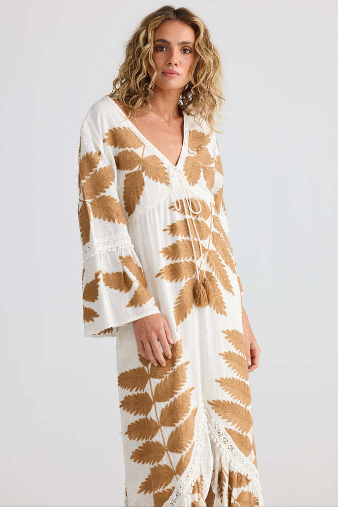 Woman wearing a white dress with brown leaf pattern on a white background