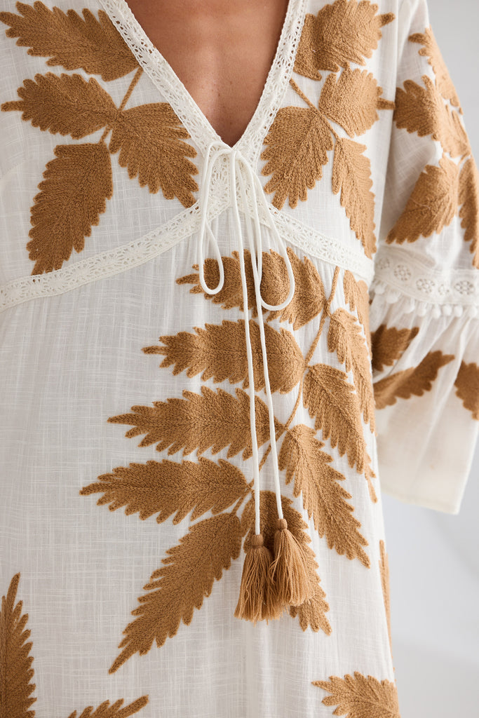 White dress with brown leaf patterns on a plain background
