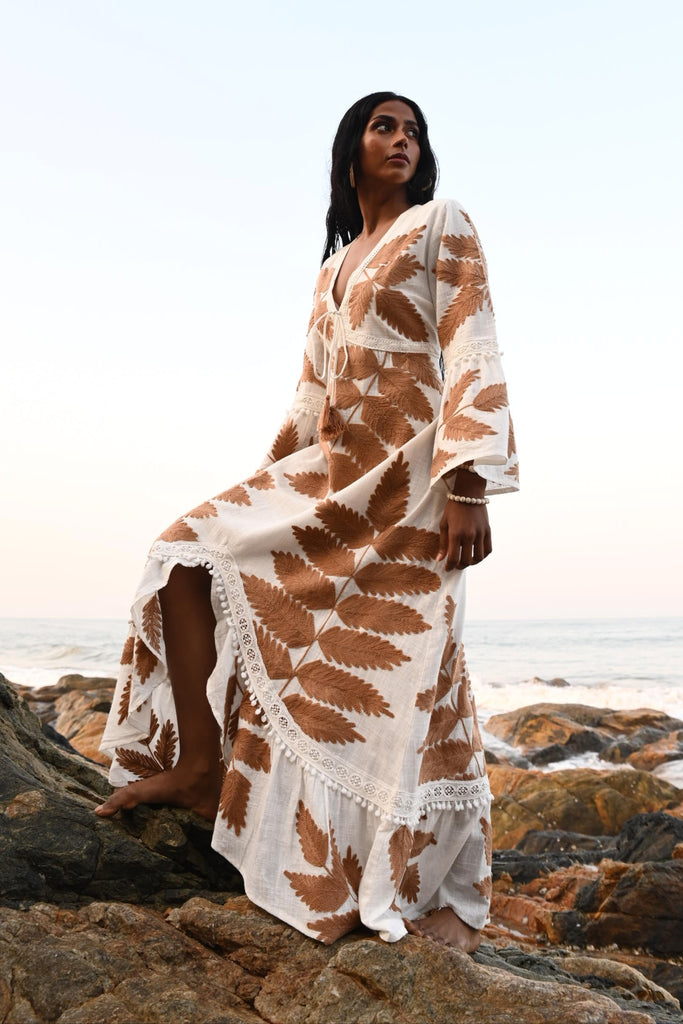 Woman wearing a patterned dress while standing on a rocky landscape, against a light blue sky
