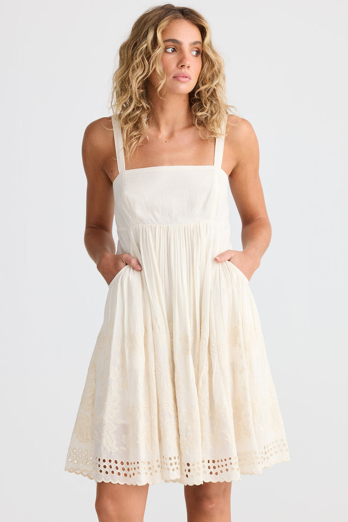 Woman wearing an off white dress with a plain background