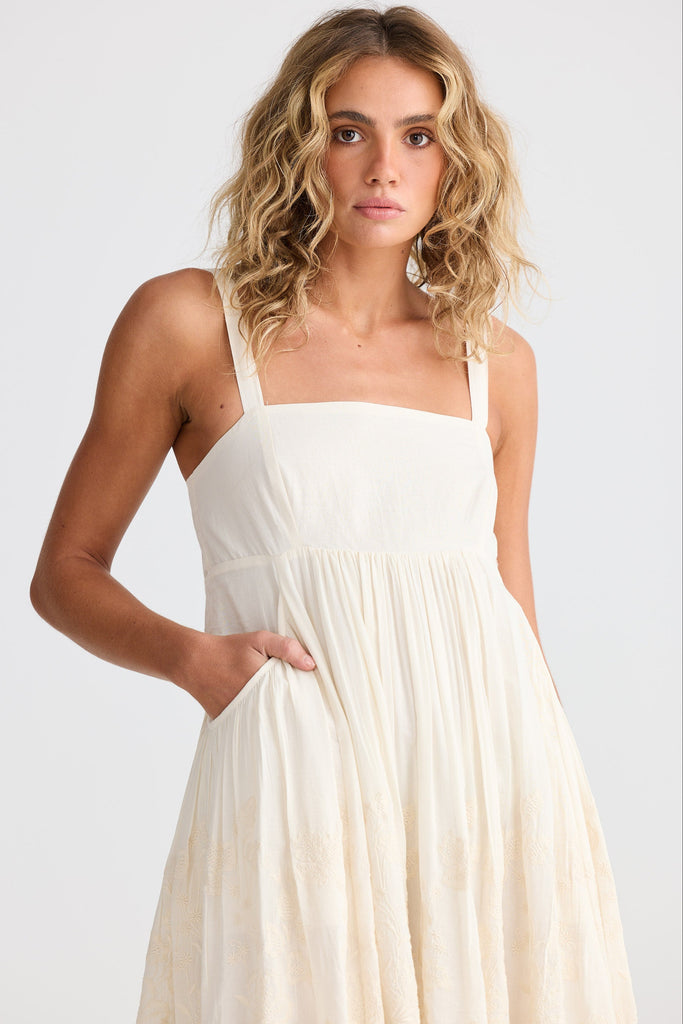 Woman wearing an off white dress against a plain background