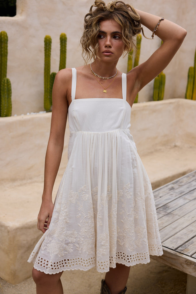 Woman wearing a white dress with a cactus background