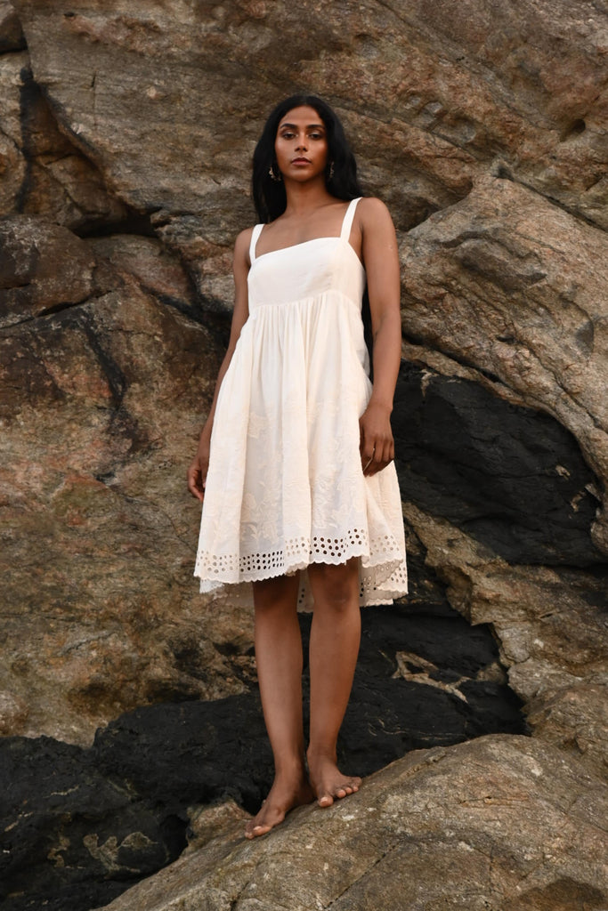 Woman in an off white dress standing on rocky terrain