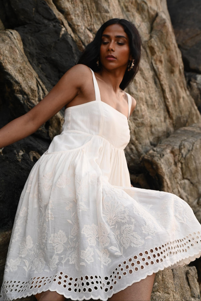 Woman in an off white dress standing among rocks
