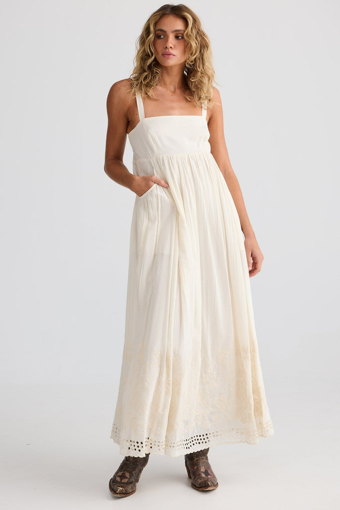 Woman wearing an off white dress on a plain background
