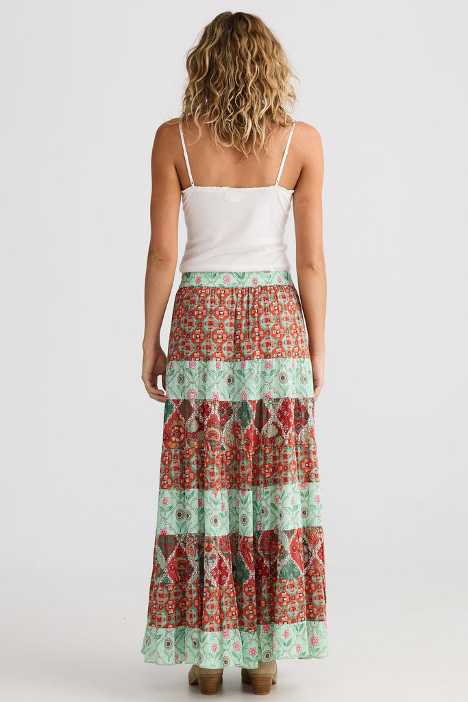 Woman wearing a white top and patterned skirt on a white background