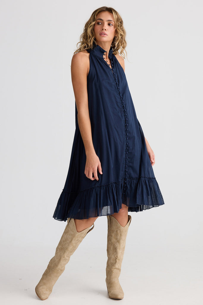 Woman wearing a navy dress with beige knee-high boots on a white background