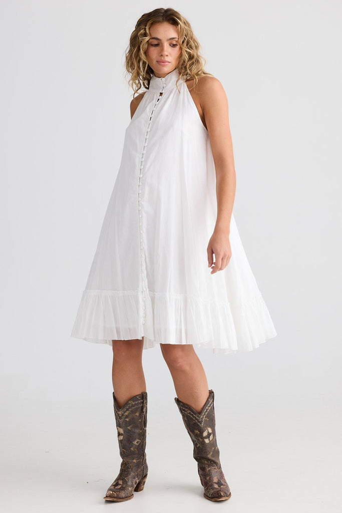 Woman wearing a white dress and patterned boots on a plain background