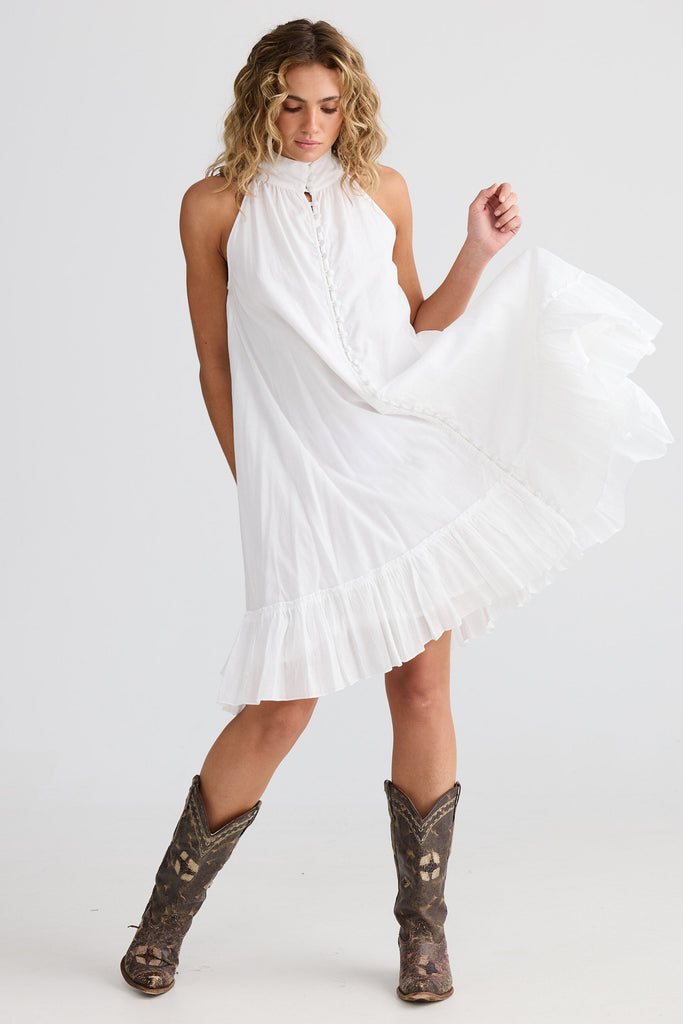 Woman wearing a white dress and brown boots on a white background