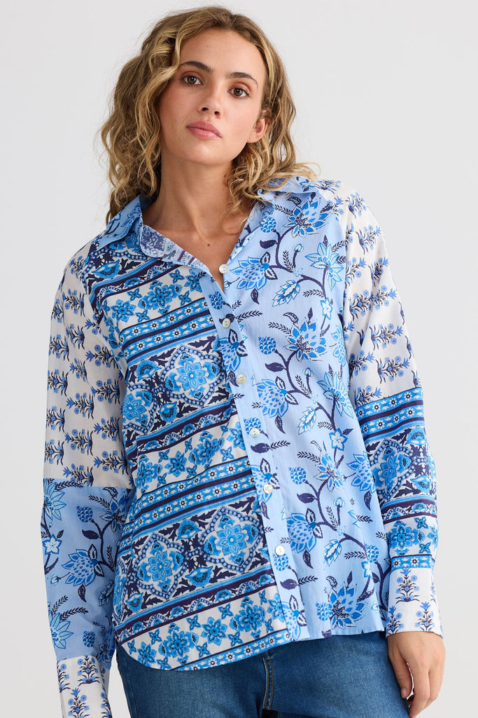Woman wearing a blue floral patterned shirt against a white background