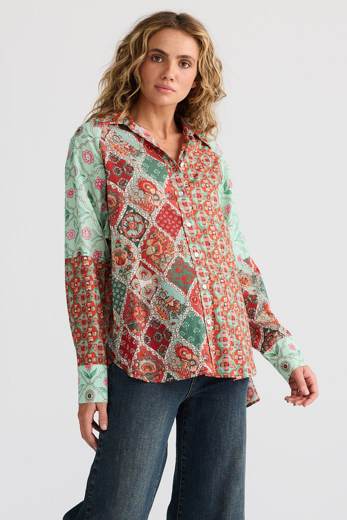 Woman wearing a patterned blouse and blue jeans on a white background