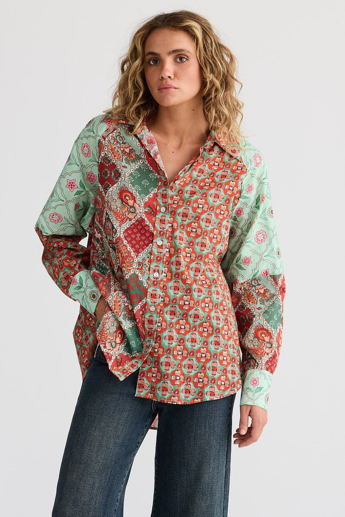 Woman wearing a patterned blouse and blue jeans on a white background
