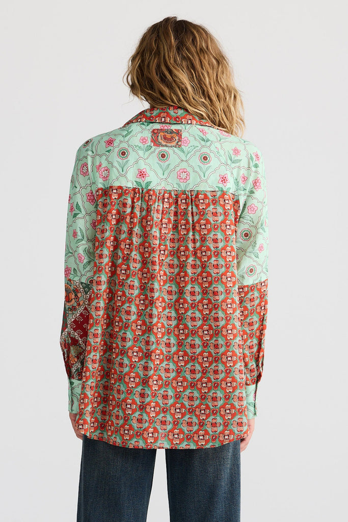 Person wearing a patterned shirt and jeans on a white background