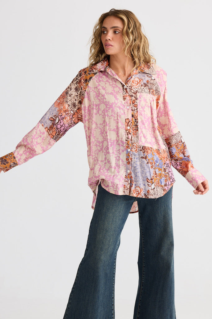 Woman wearing a patterned blouse and jeans on a white background