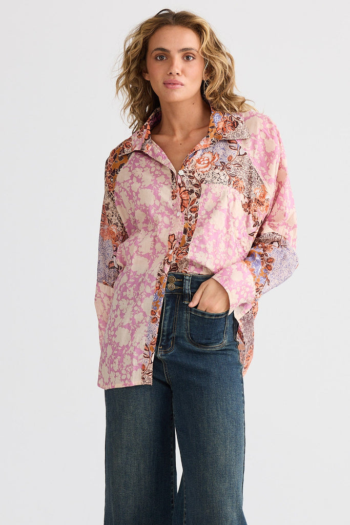 Woman wearing a patterned shirt and blue jeans on a white background