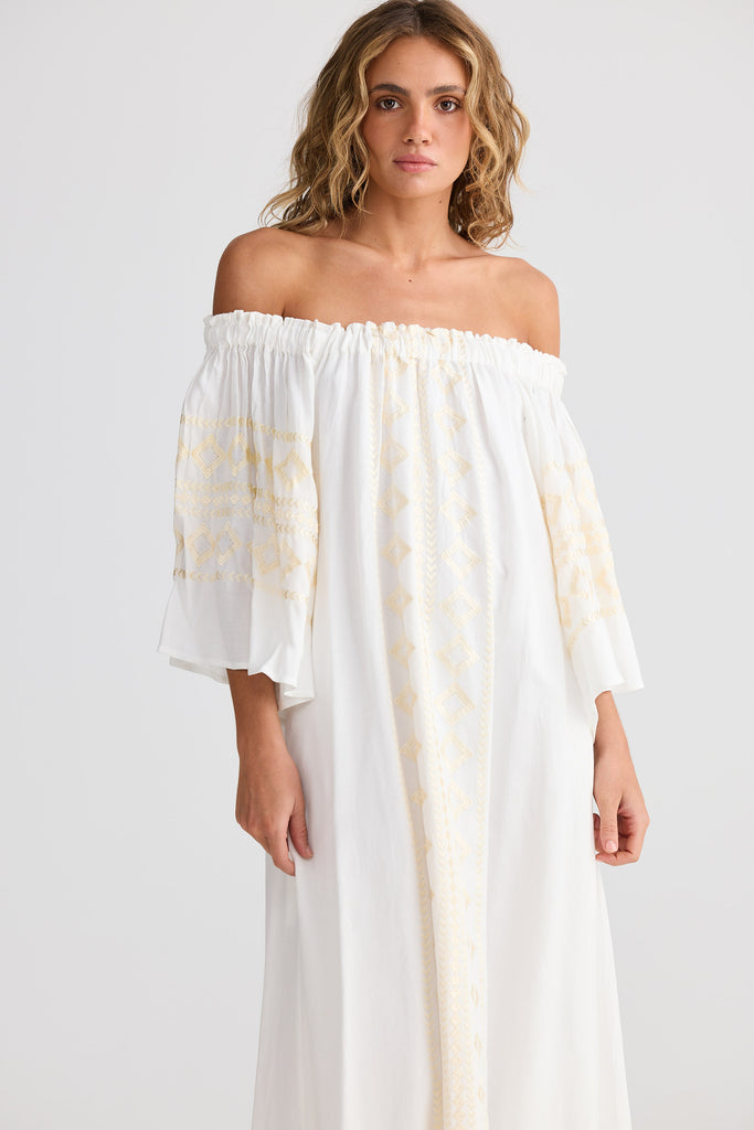 Woman wearing a white off-shoulder dress with yellow patterns on a white background