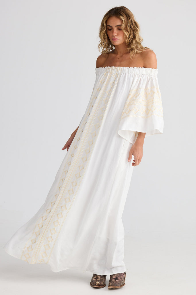 Woman wearing a white off-shoulder dress on a plain background