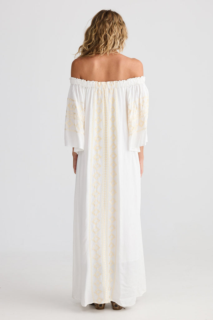 Woman wearing a white off-shoulder dress on a plain background