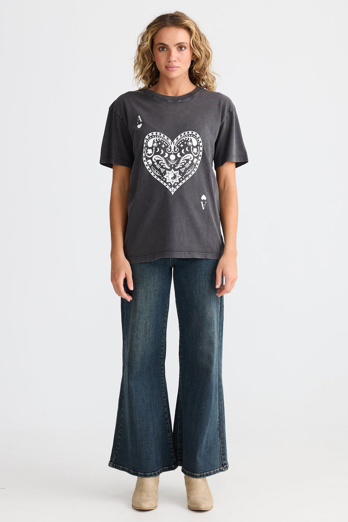 Woman wearing a dark gray t-shirt with a heart design and blue jeans on a white background