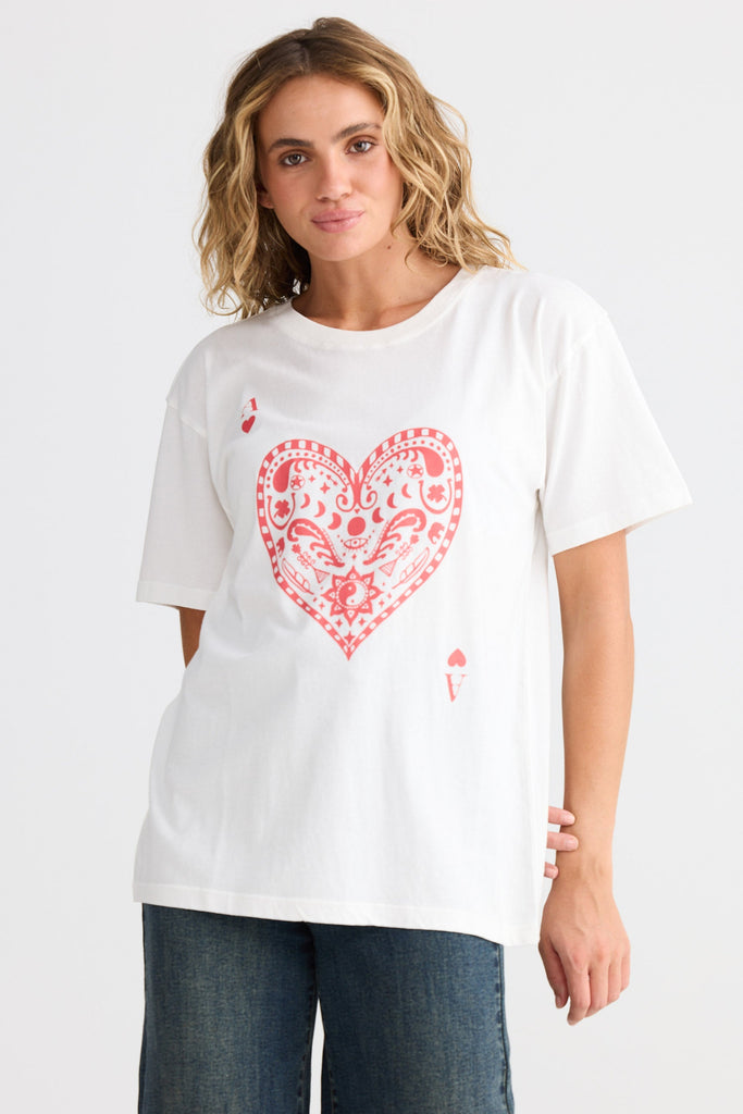 Woman wearing a white t-shirt with a red heart design on a plain background