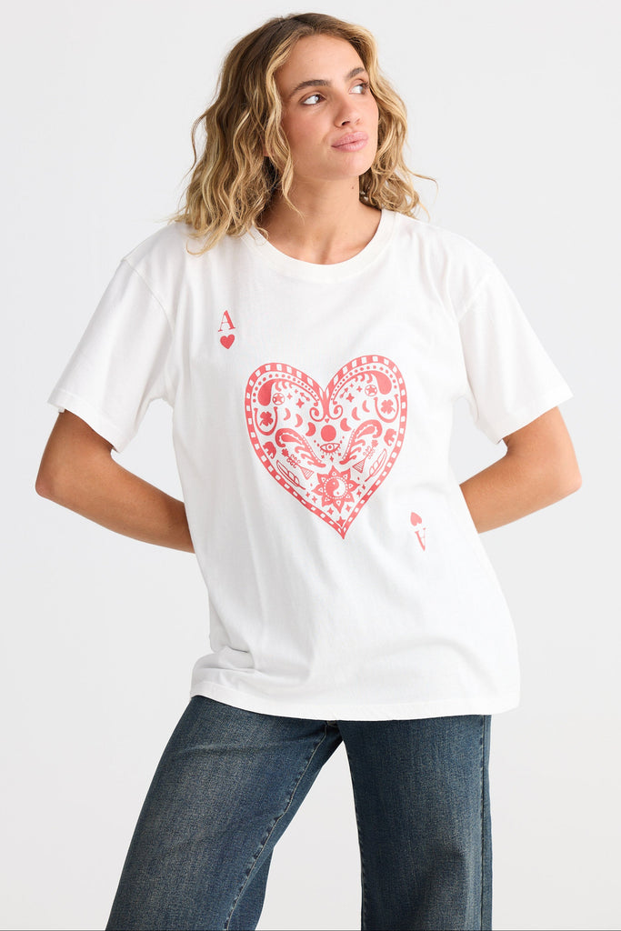 Woman wearing a white t-shirt with a red heart design on a plain background