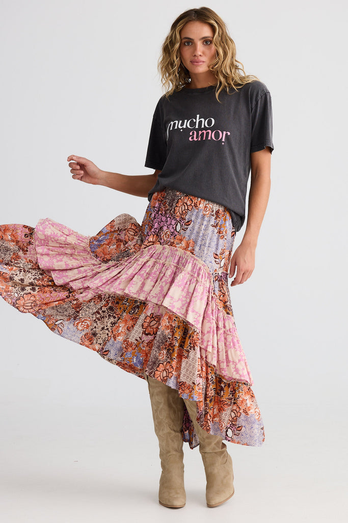Woman wearing a colorful skirt and black t-shirt with 'mucho amor' text on a white background