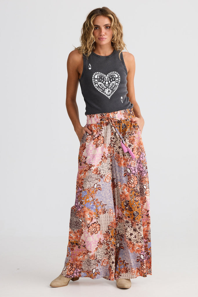 Woman wearing a tank top with a heart design and a floral skirt on a white background