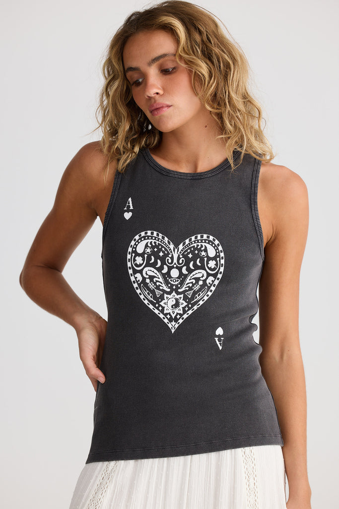 Woman wearing a black tank top with a white heart design on a plain background