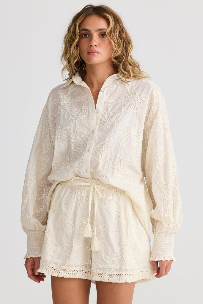 Woman wearing a cream-coloured outfit on a white background