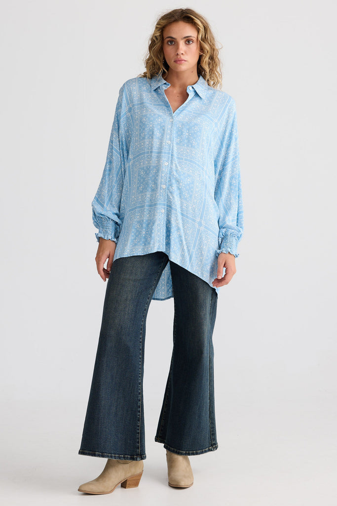 Woman wearing a light blue shirt and dark jeans on a white background
