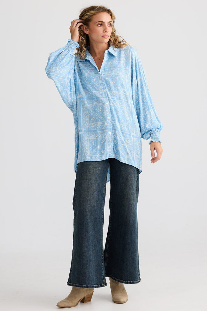 Woman wearing a light blue shirt and dark jeans on a white background