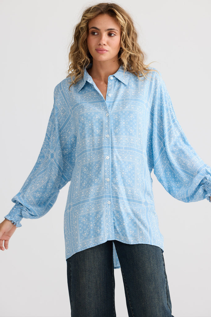 Woman wearing a light blue patterned shirt against a white background
