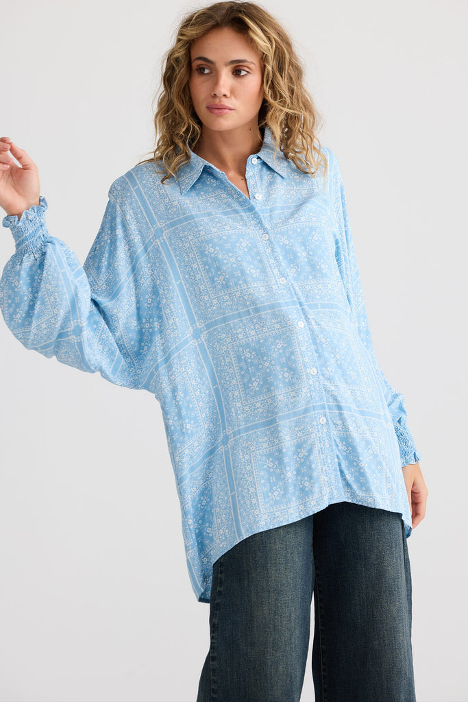 Woman wearing a light blue shirt with rolled-up sleeves on a white background