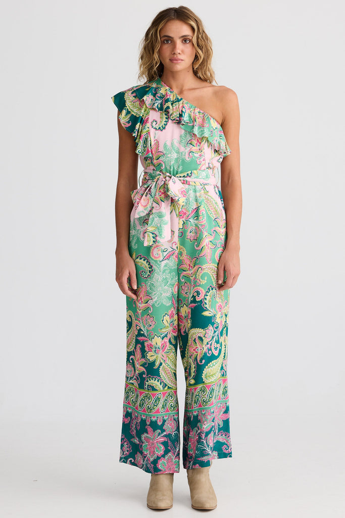 Woman wearing a floral one-shoulder jumpsuit on a white background