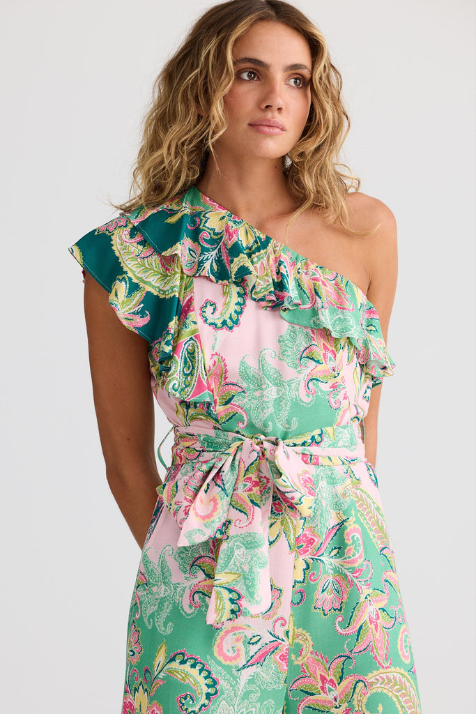 Woman wearing a colorful one-shoulder jumpsuit on a white background