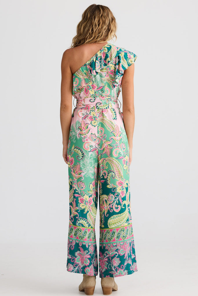 Woman wearing a colorful one-shoulder jumpsuit on a white background