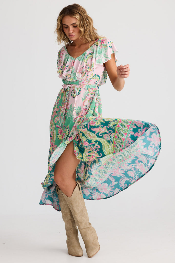 Woman wearing a colorful patterned dress with beige knee-high boots on a white background