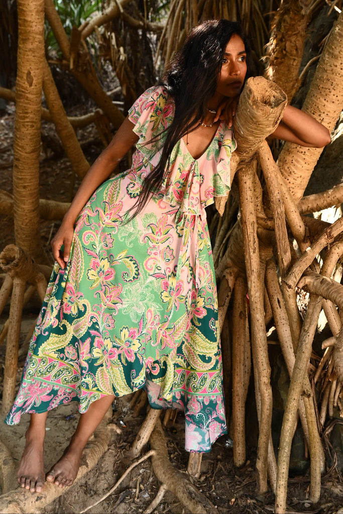 Woman in a floral dress standing among tree roots