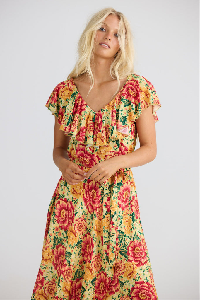 Woman wearing a colorful floral dress on a plain background