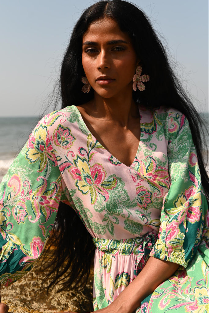 Woman wearing a floral dress sitting on a rock with a clear blue sky in the background