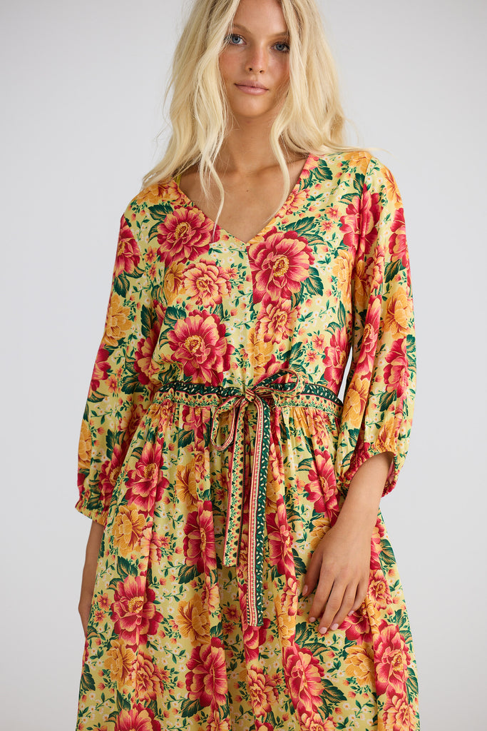 Woman wearing a colorful floral dress on a plain background