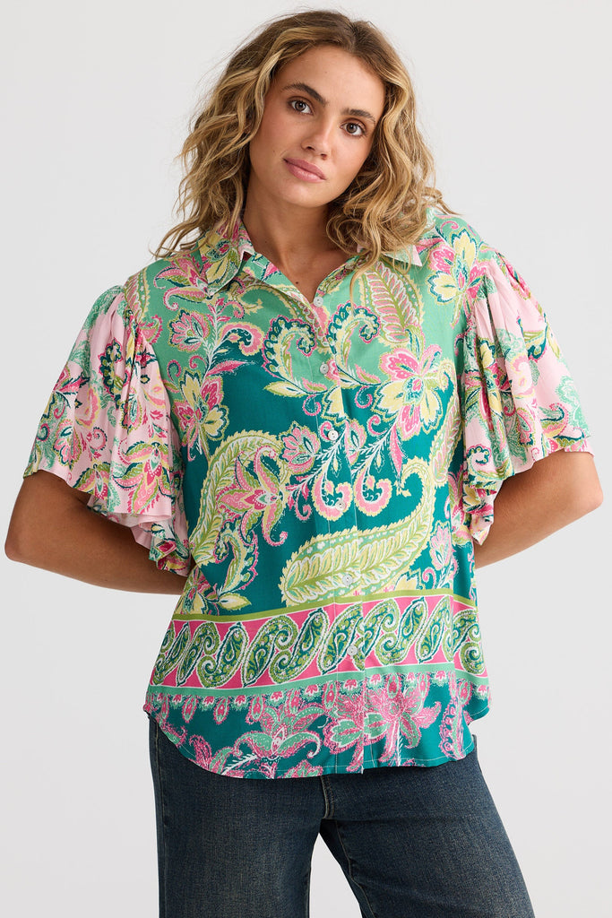 Woman wearing a colorful patterned blouse with a plain background