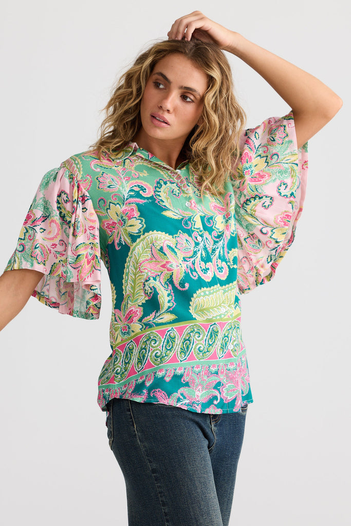Woman wearing a colorful patterned blouse with a plain background