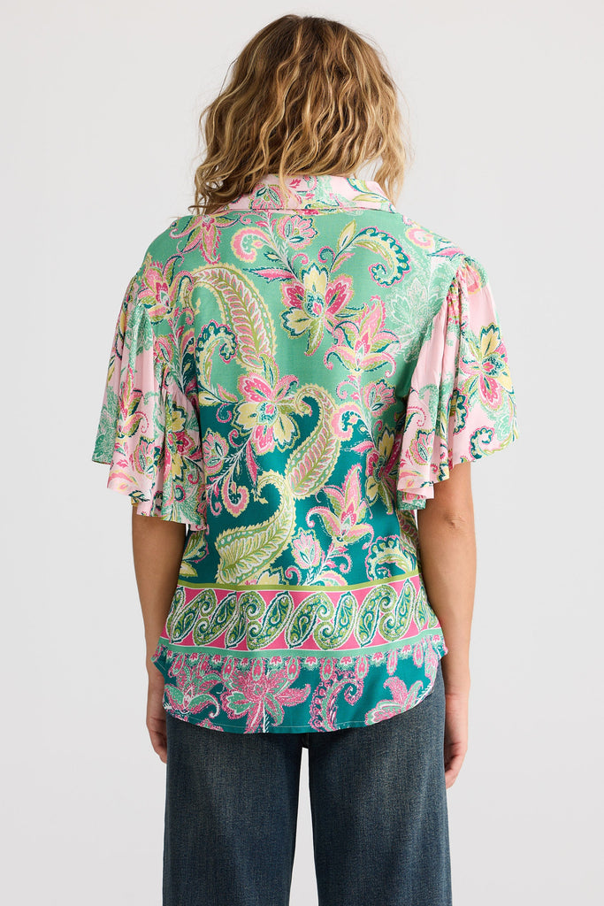 Person wearing a colorful paisley blouse with a white background