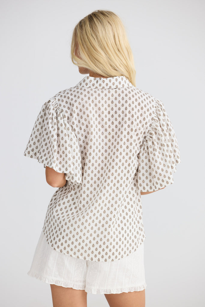 Woman wearing a white blouse with a subtle pattern on a plain background