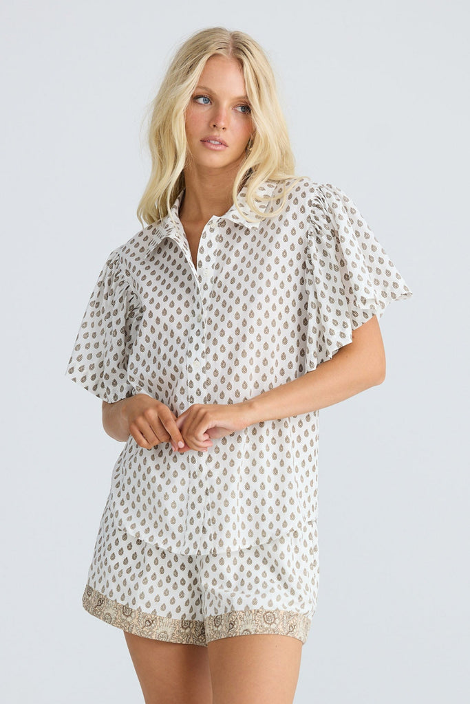 Woman wearing a polka patterned shirt and matching shorts on a white background