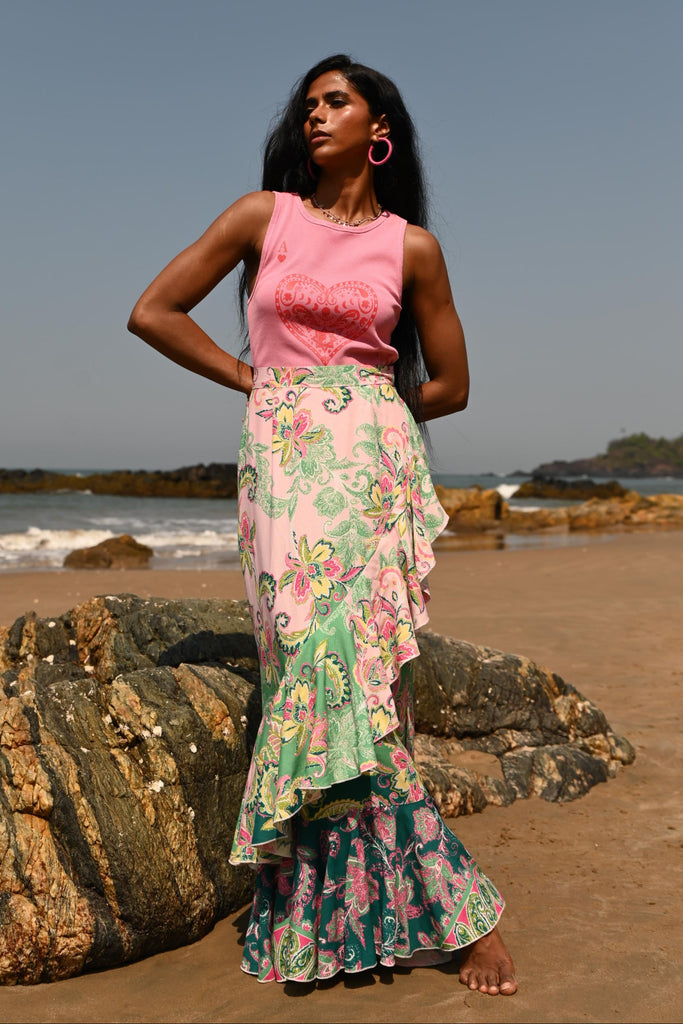 Woman in a floral dress standing on a sandy beach with a clear blue sky in the background