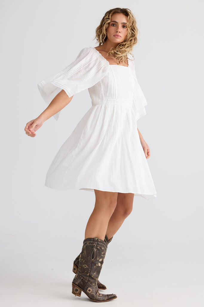 Woman wearing a white dress and brown boots on a white background
